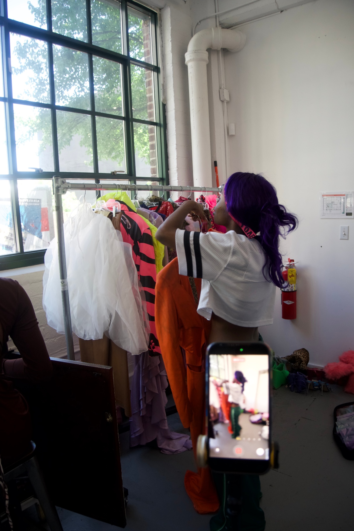 Stylist pulling looks from a colorful wardrobe rack backstage