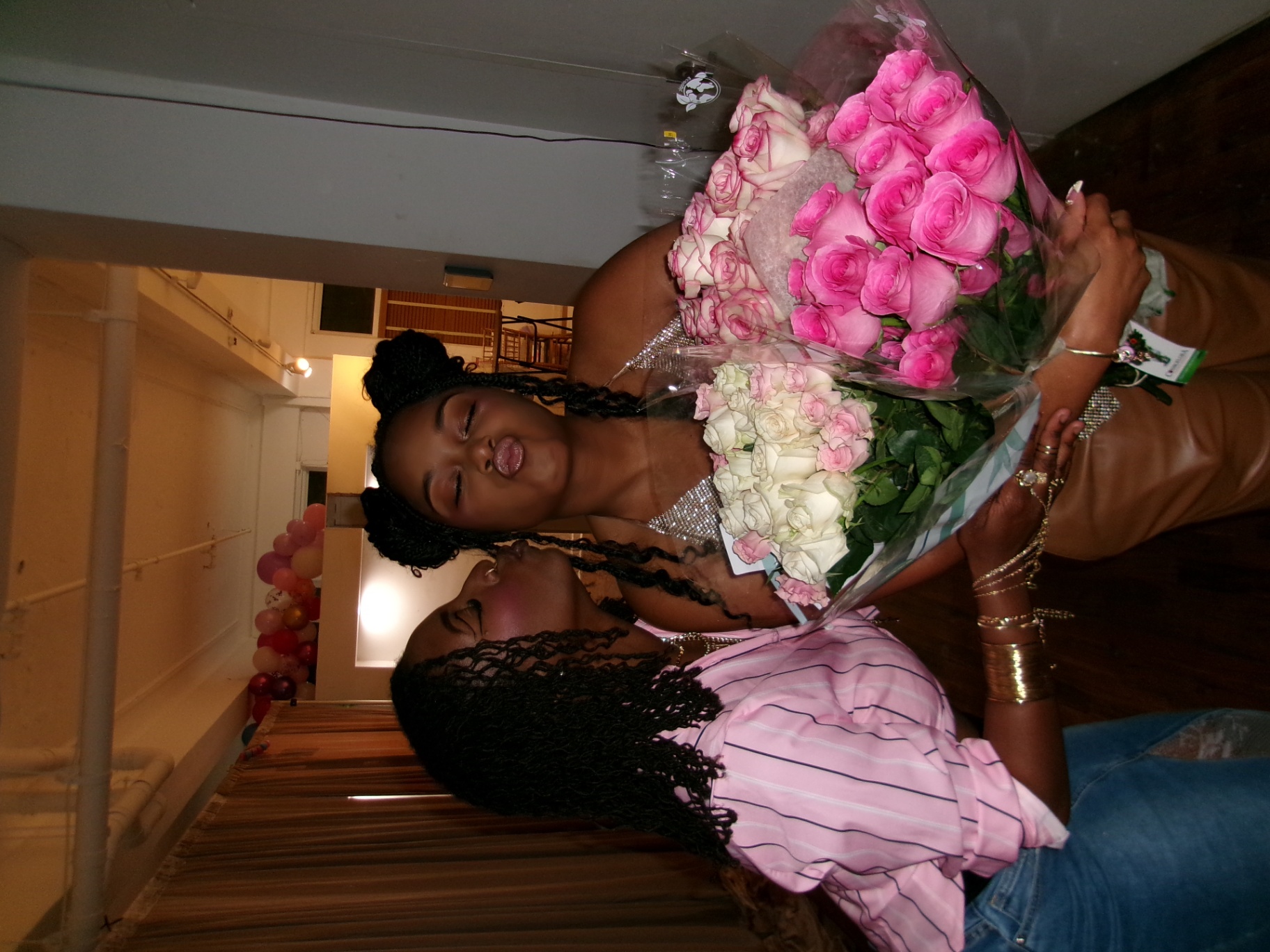 Host holding a giant bouquet of pink roses with a friend