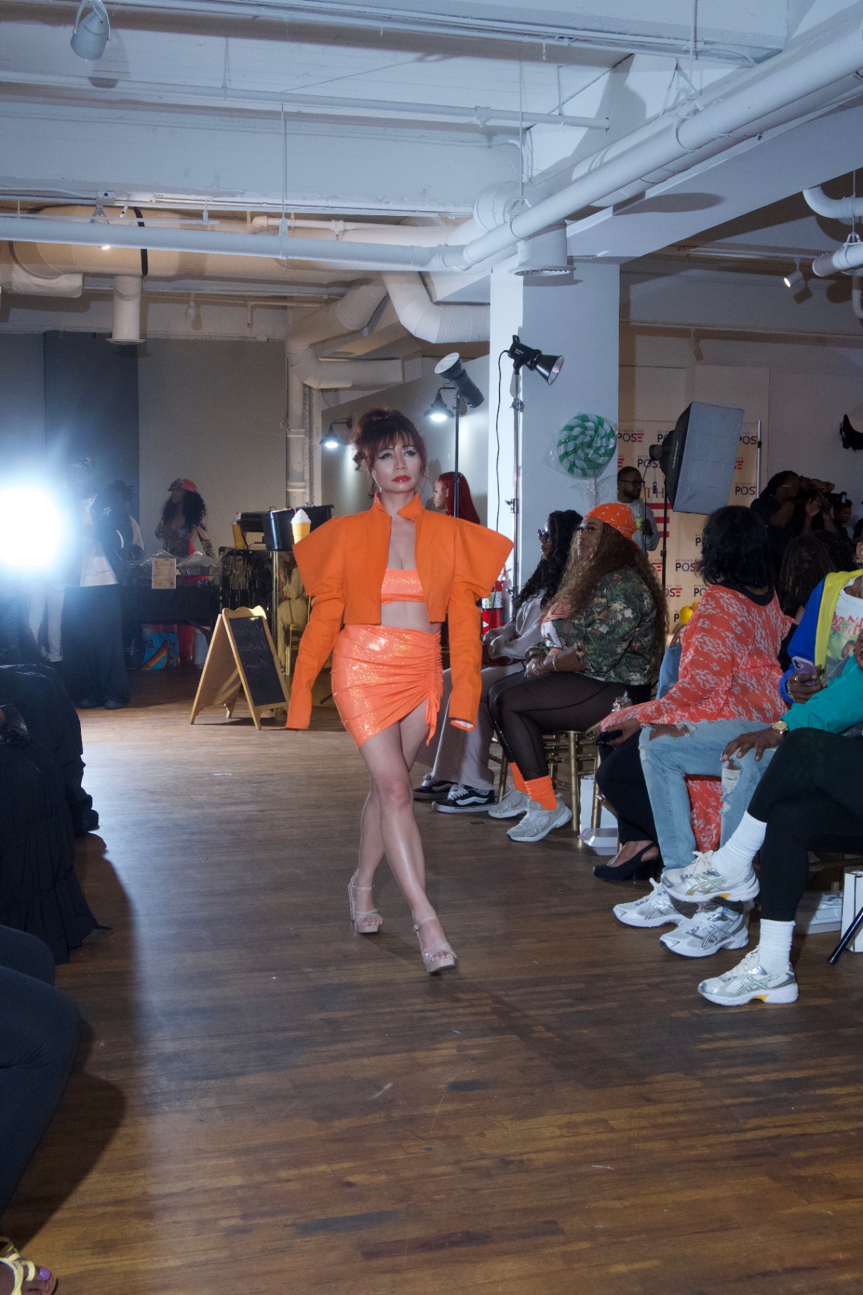 Model in an orange cropped blazer and mini skirt walking the runway