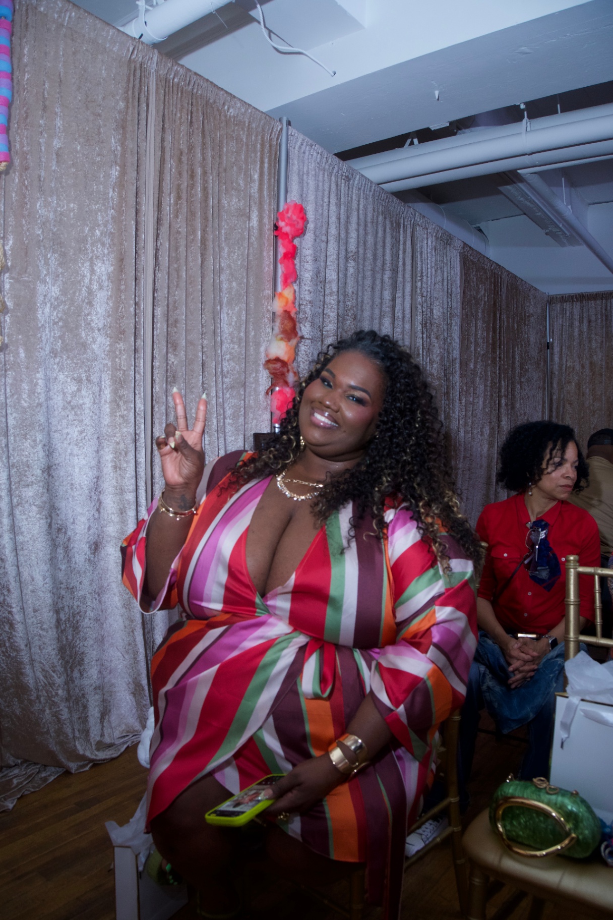 Guest in a colorful striped satin dress throwing a peace sign