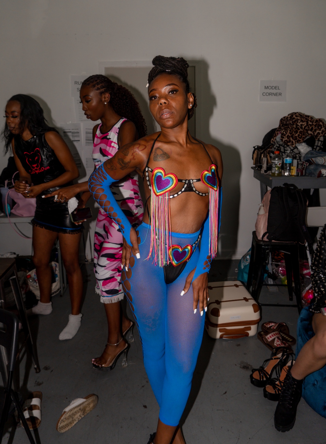 Model in a rainbow fringe top and blue mesh set posing in the model corner