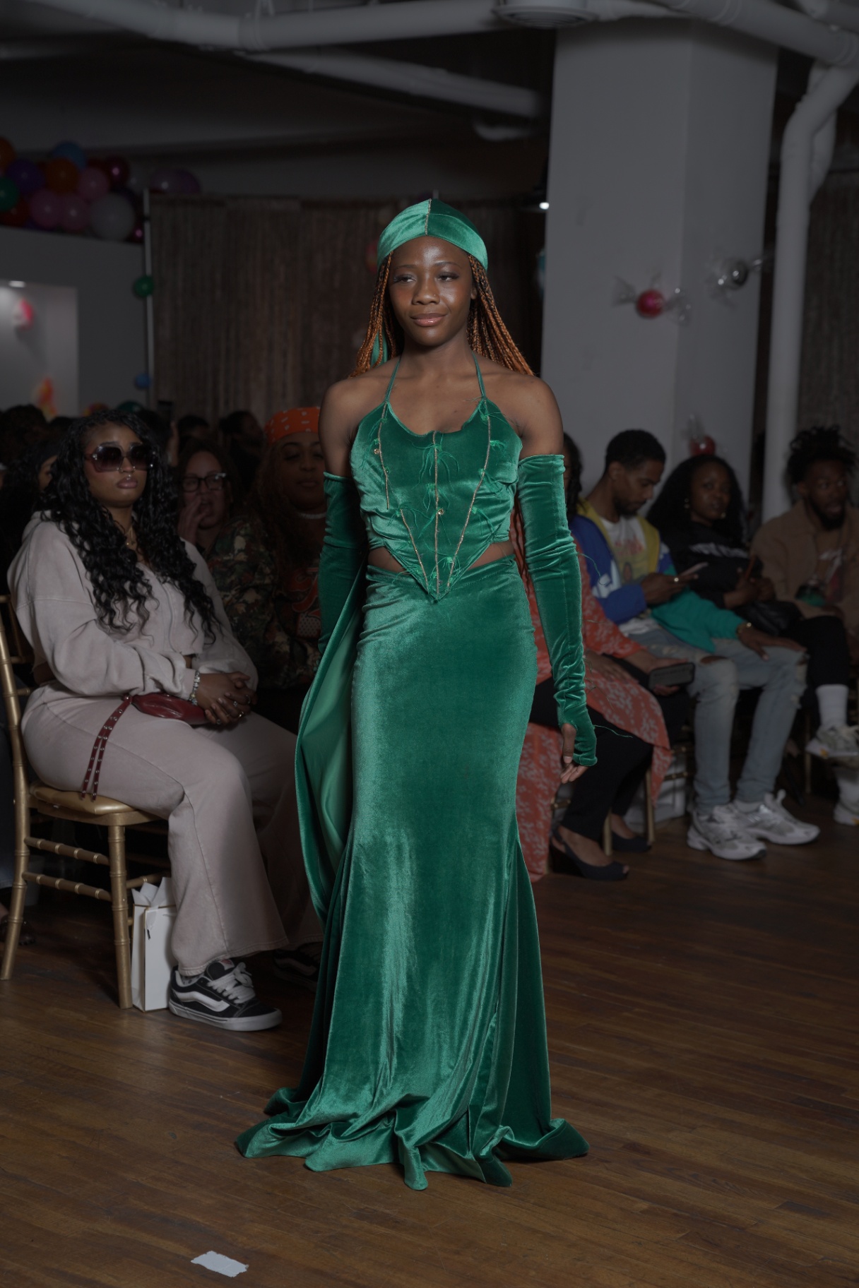 Model in an emerald green velvet halter gown with head wrap