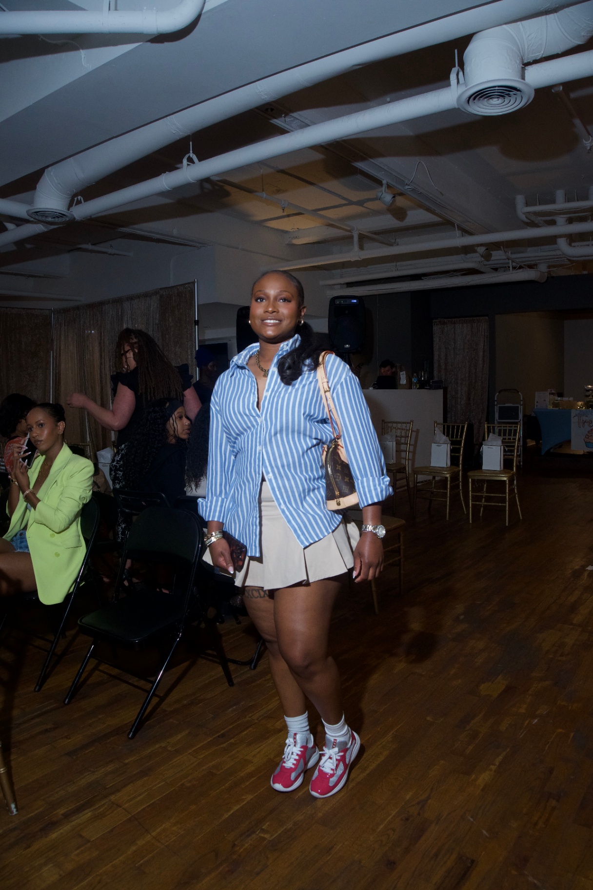 Guest in a blue striped shirt and pleated skirt walking through the venue
