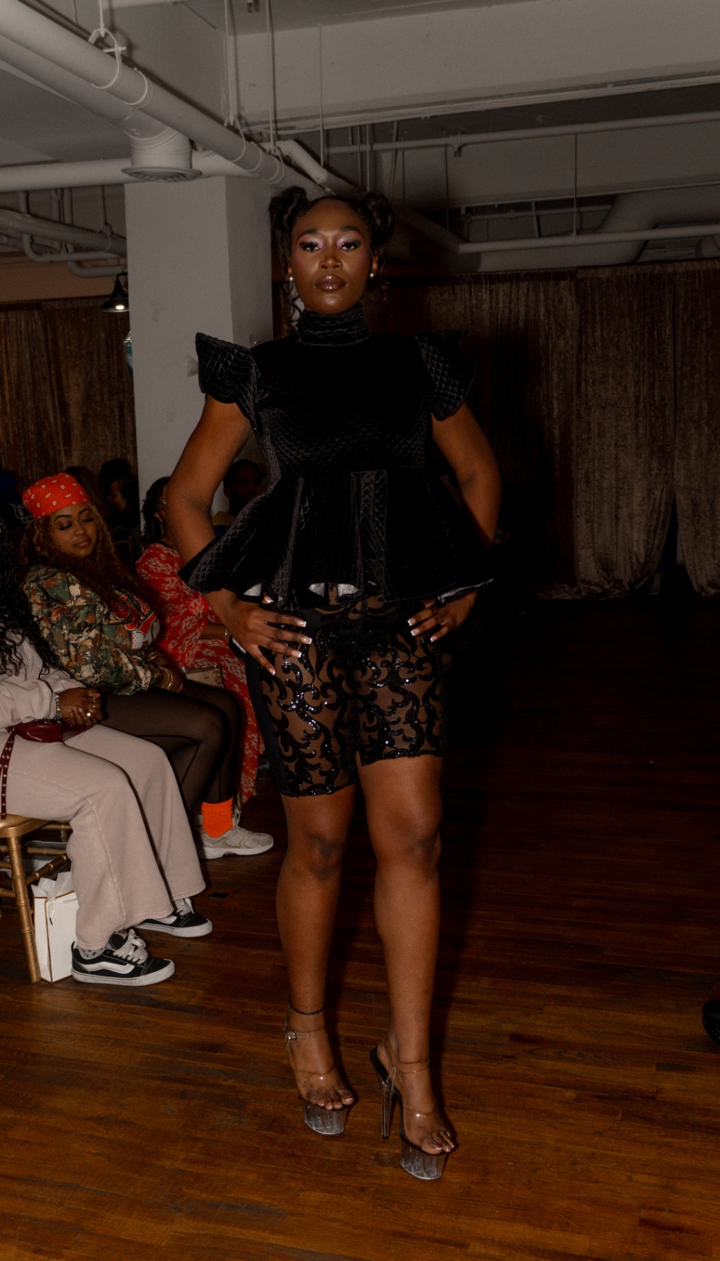 Model in a black velvet peplum top and sheer sequined shorts