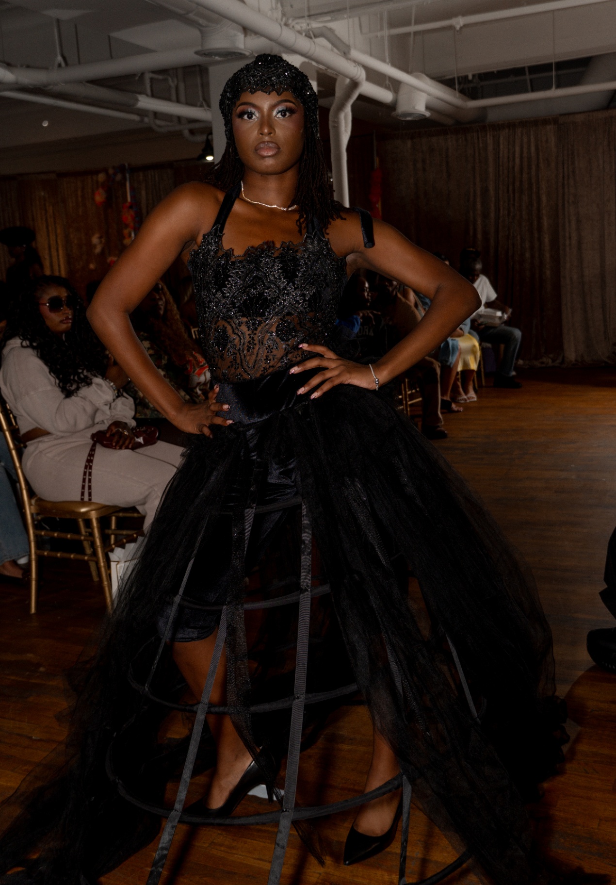 Model in a beaded black corset top and tulle cage skirt with jeweled headpiece