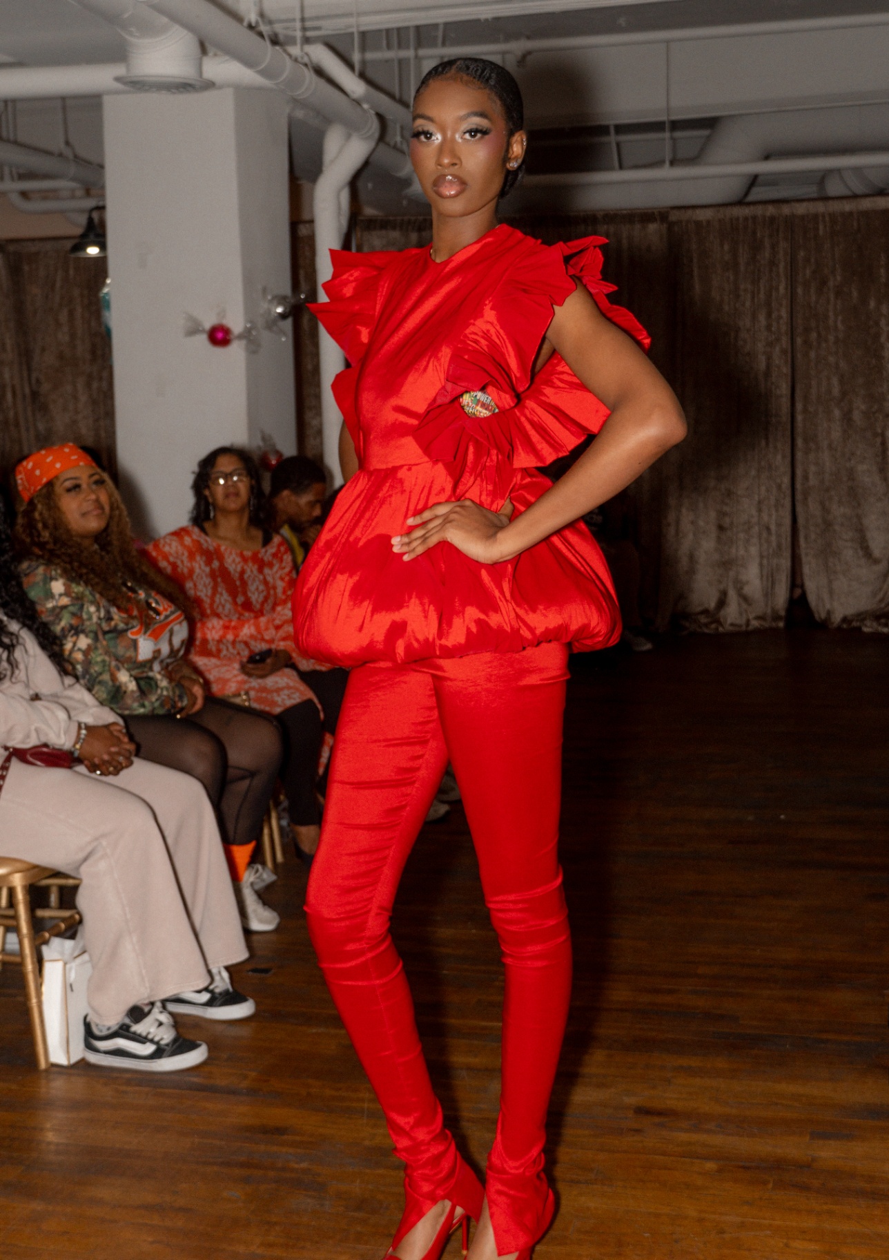 Model in a red ruffled peplum top and satin red pants with matching boots