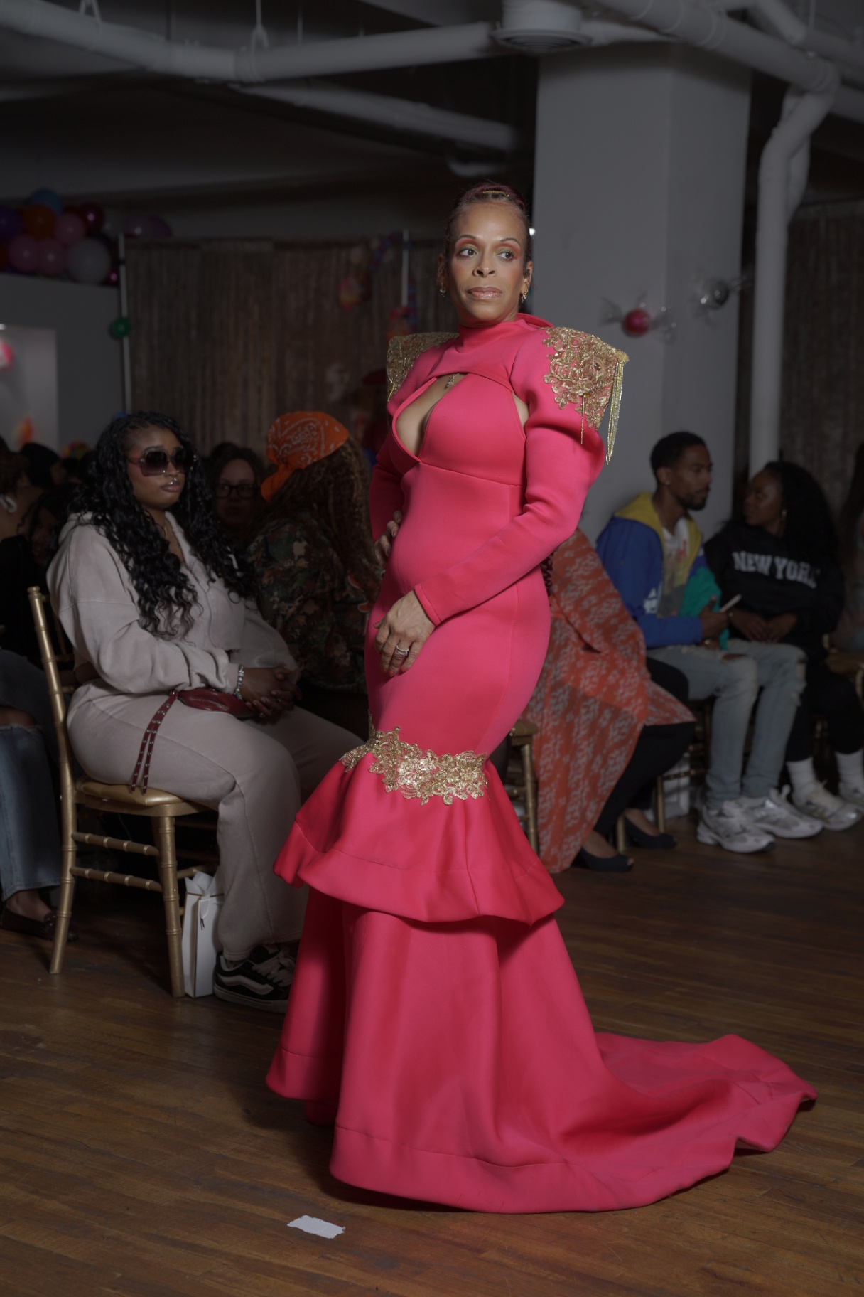 Model in a hot pink mermaid gown with gold appliqué shoulders