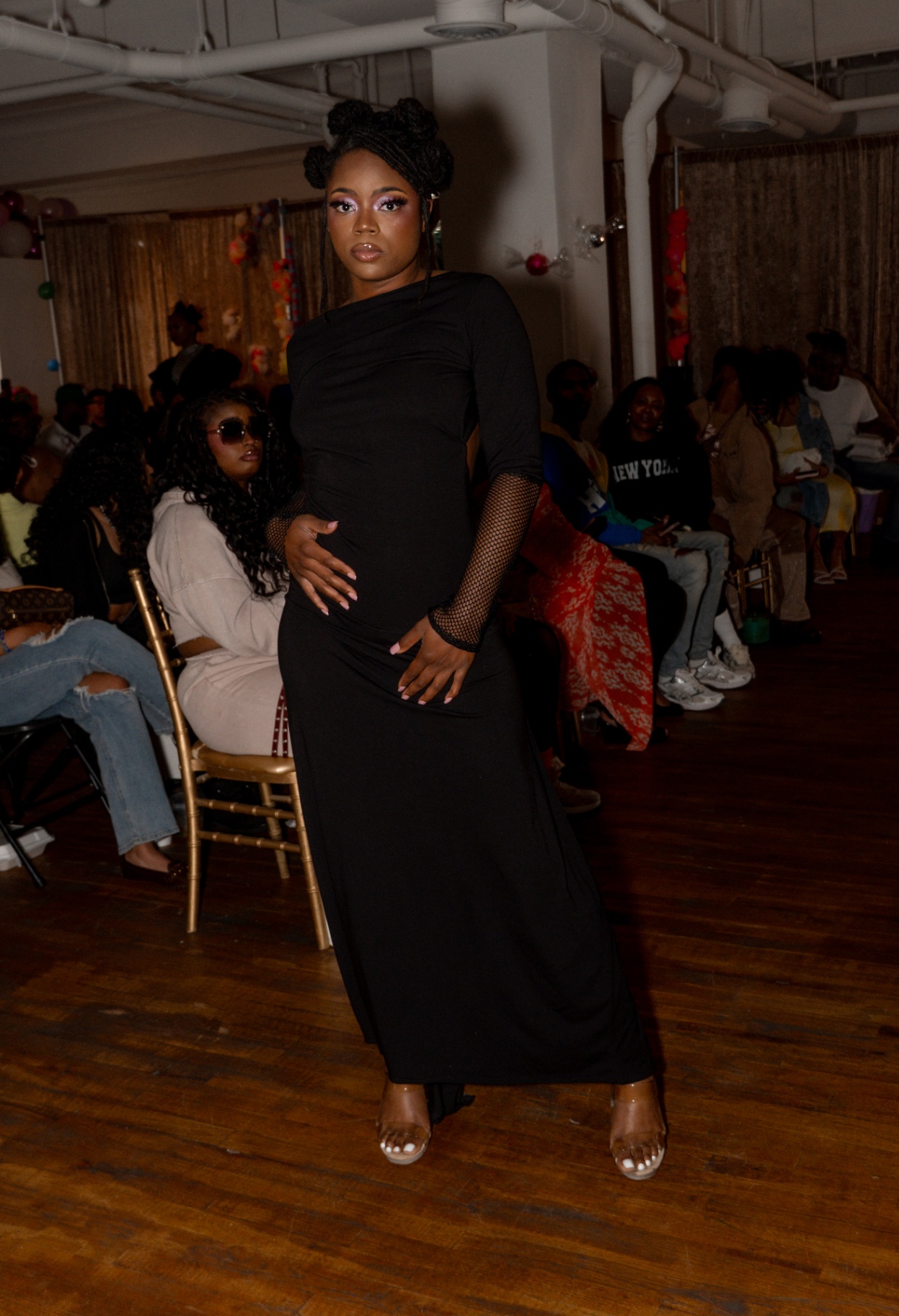 Model in a long-sleeved black maxi dress with fishnet sleeve detail