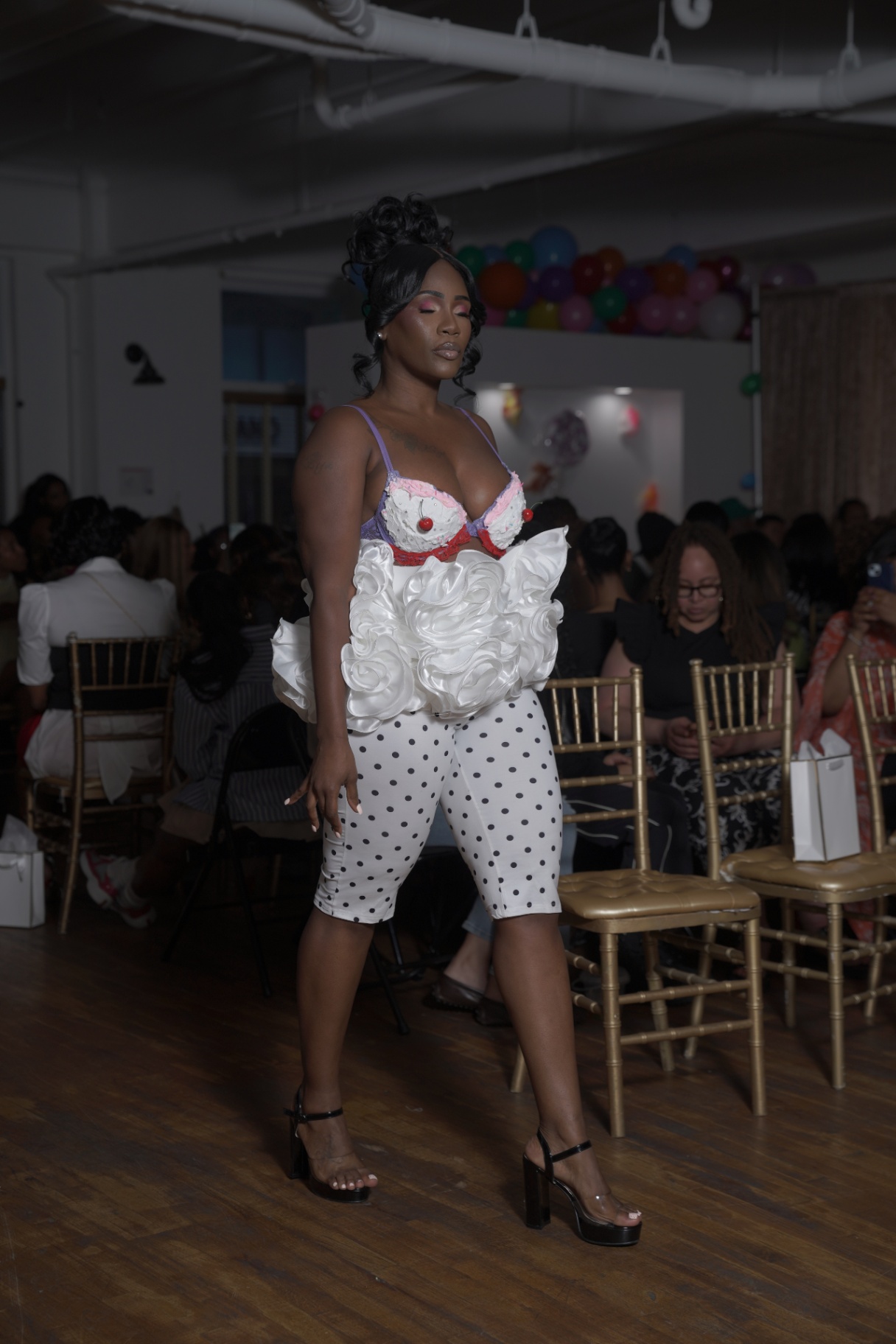 Model in a cake-inspired corset top and polka-dot capris on the runway