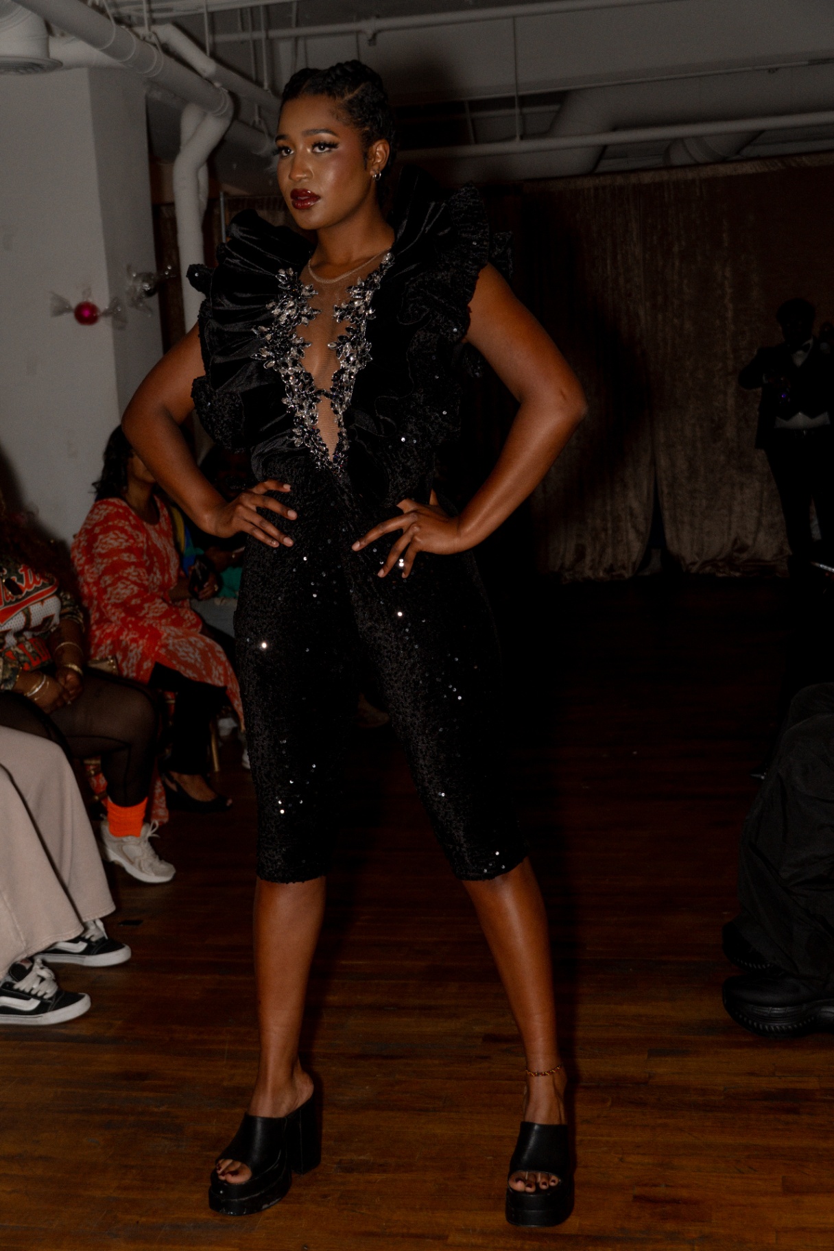 Model in a black ruffled sequin jumpsuit with crystal neckline