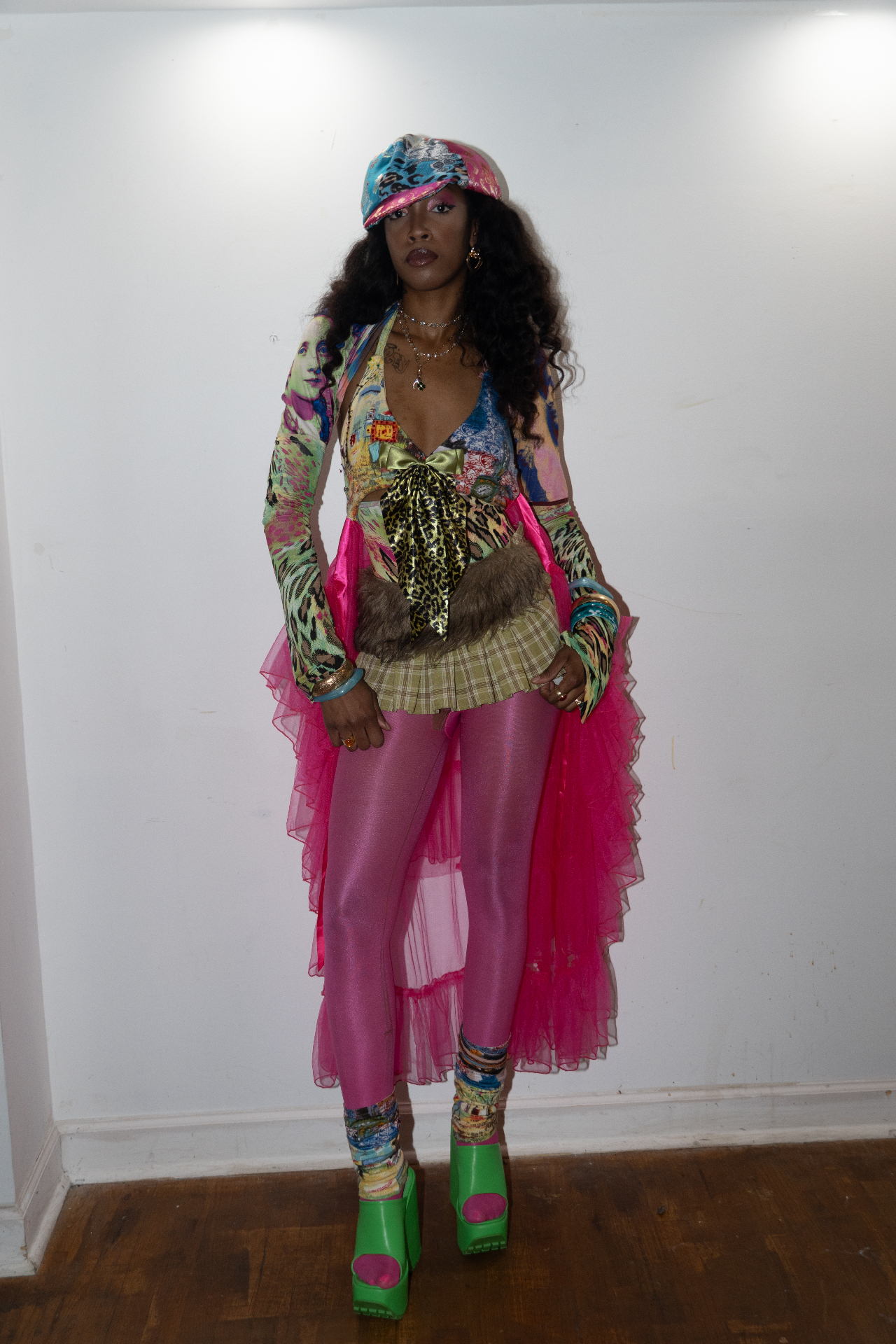 Model in a printed patchwork set with pink tulle skirt, cap, and green platform heels