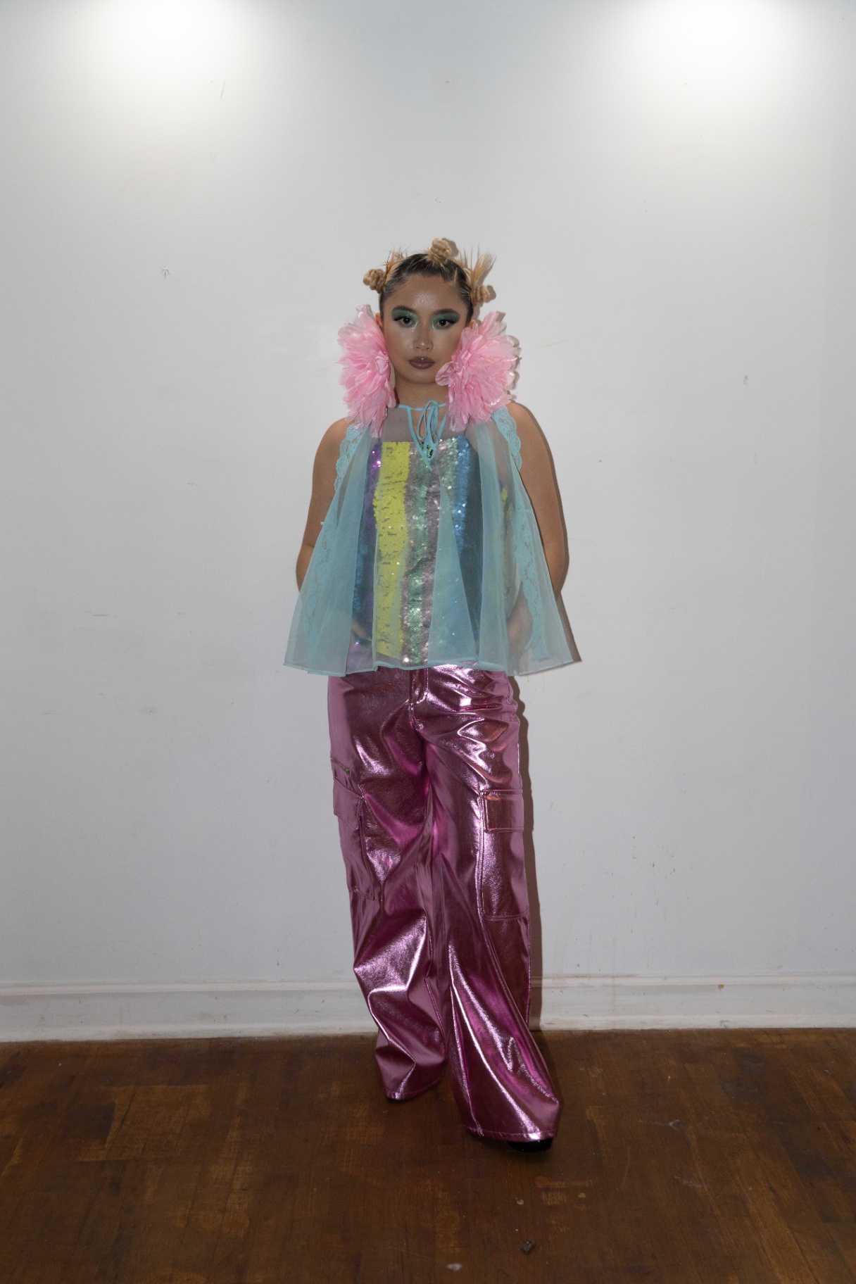 Model in a sequin top and metallic pink cargo pants with pink tulle shoulder pieces