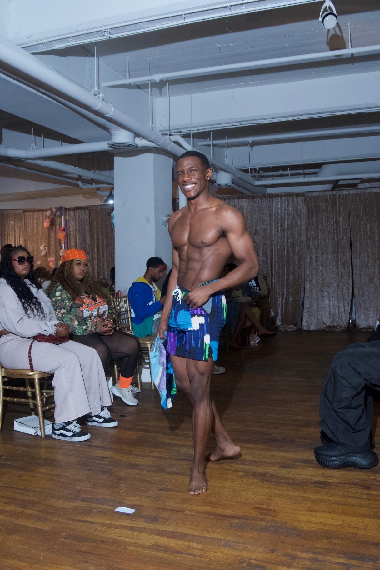 Model in printed swim shorts walking the runway barefoot