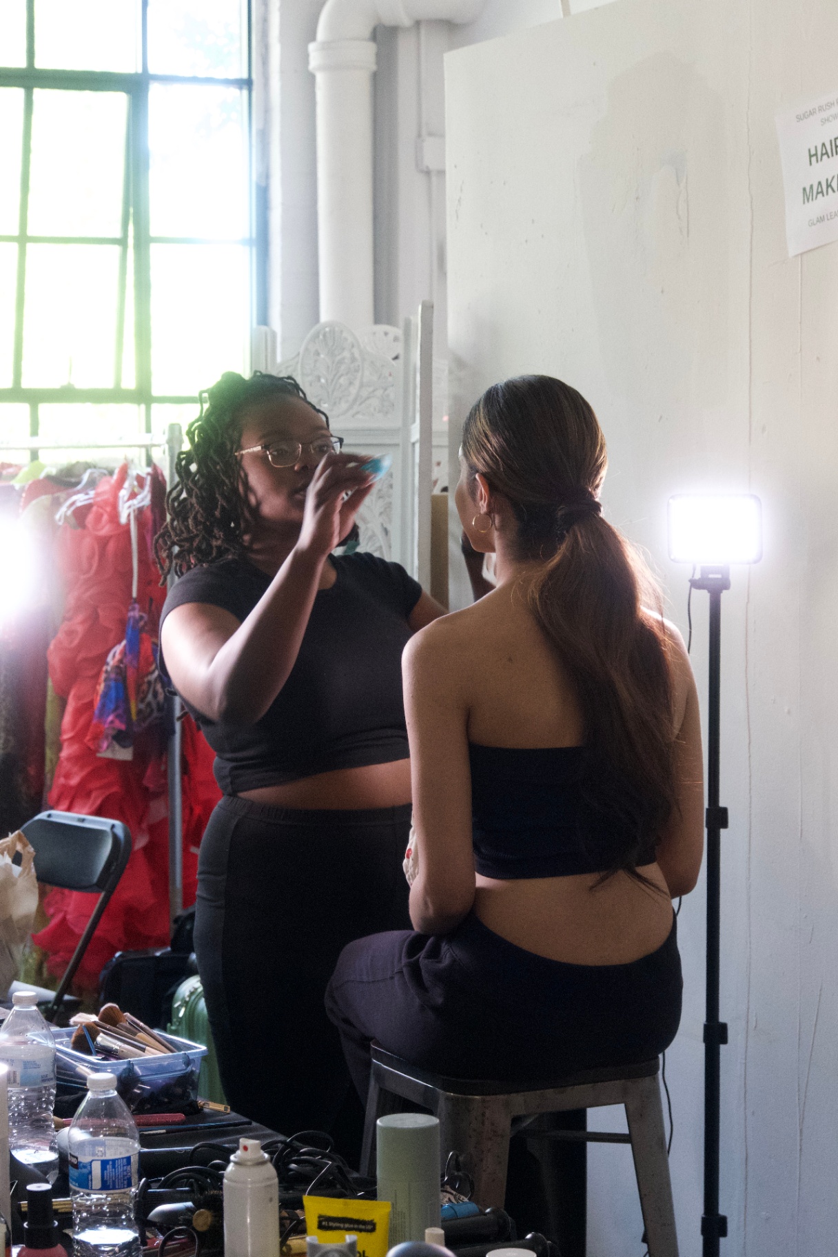 Makeup artist finishing touches on a model at the vanity